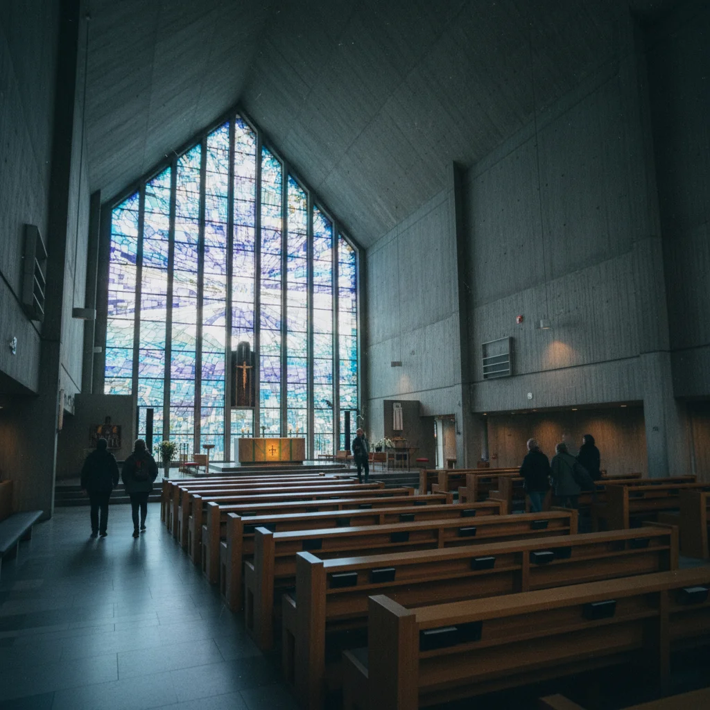 Innenansicht der Eismeerkathedrale mit Betonwänden, Holzbänken und Glasfenster